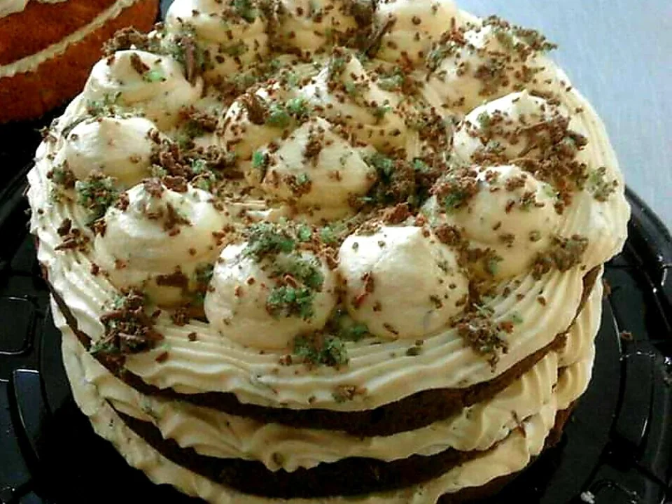 A layered Mr Bake cake topped with piped fresh cream and chocolate crumbs.