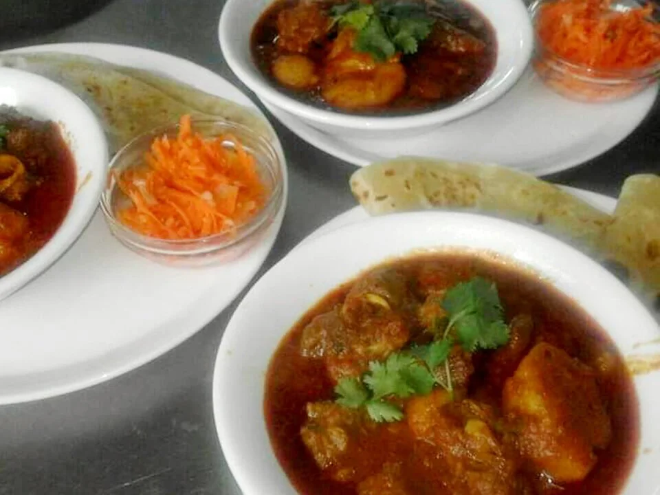 Mr Bake curry meals served with accompaniments on white plates.